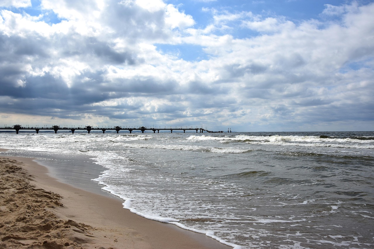 Molo w Międzyzdrojach widziane z plaży, fale i pochmurne niebo nad Bałtykiem